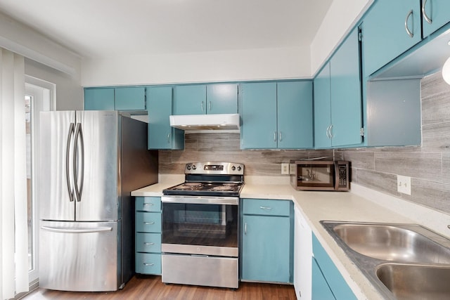 kitchen with appliances with stainless steel finishes, light countertops, blue cabinets, and under cabinet range hood