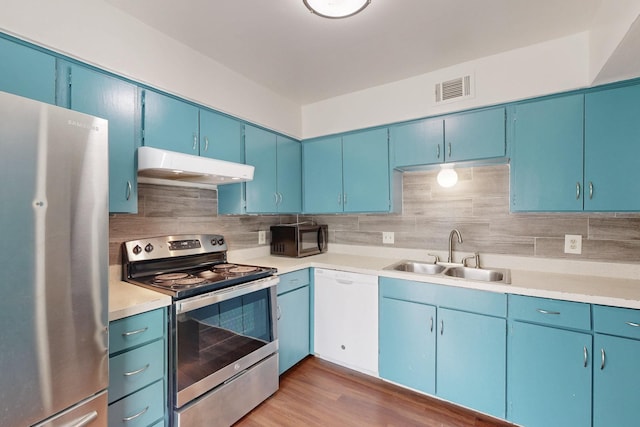 kitchen featuring appliances with stainless steel finishes, light countertops, a sink, and under cabinet range hood