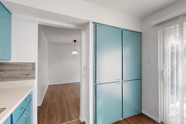 kitchen with blue cabinetry, baseboards, dark wood-type flooring, and decorative light fixtures