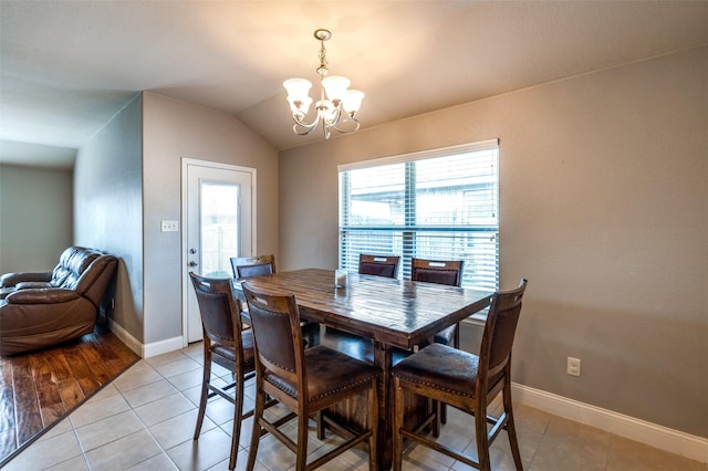 tiled dining room featuring an inviting chandelier and lofted ceiling