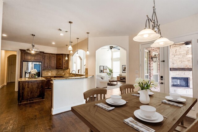 11043 Riney Ct, Frisco, TX 75035 - dining space featuring arched walkways, dark wood-type flooring, a ceiling fan, a fireplace, and recessed lighting
