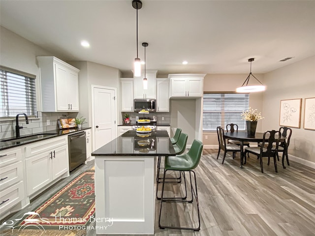 kitchen featuring sink, white cabinetry, a center island, hanging light fixtures, and appliances with stainless steel finishes