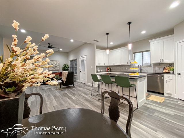 kitchen featuring white cabinets, decorative light fixtures, a breakfast bar area, and dishwasher