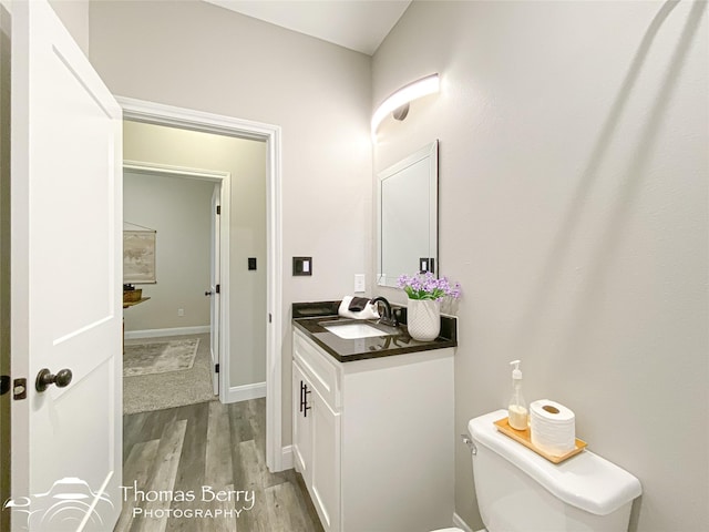 bathroom with wood-type flooring, toilet, and vanity