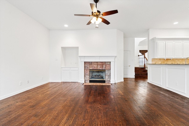 unfurnished living room with dark wood-type flooring, a fireplace, and ceiling fan