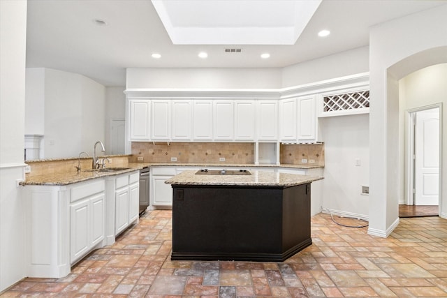 kitchen featuring backsplash, light stone countertops, kitchen peninsula, and white cabinets