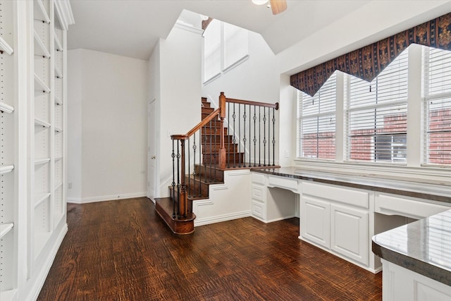 unfurnished office featuring ceiling fan, dark hardwood / wood-style floors, and built in desk