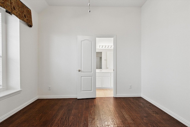 spare room with dark hardwood / wood-style flooring and lofted ceiling