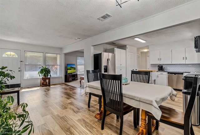 dining room with a textured ceiling and light wood-type flooring