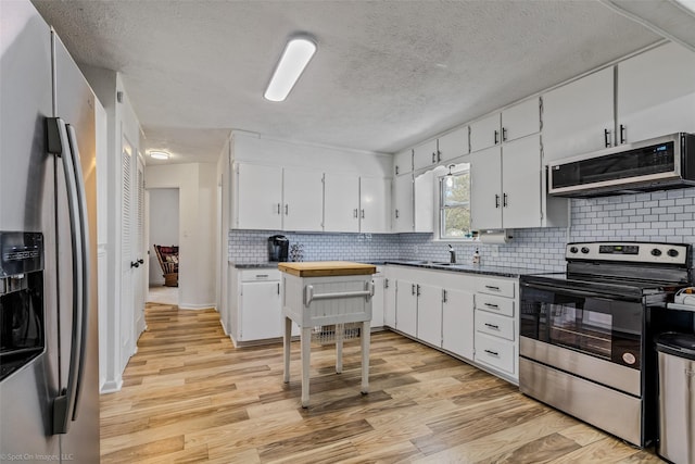 kitchen featuring stainless steel appliances, light wood-type flooring, and white cabinets