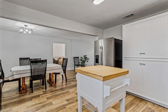 kitchen with a textured ceiling, light hardwood / wood-style floors, white cabinets, and stainless steel refrigerator with ice dispenser