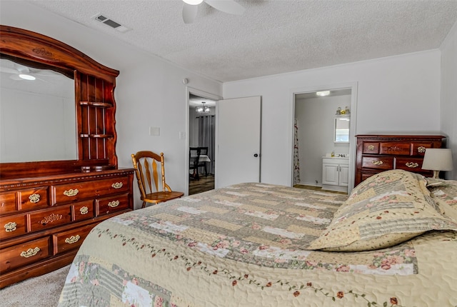 bedroom featuring ceiling fan, ensuite bath, and a textured ceiling