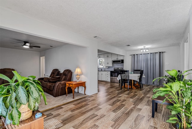 living room featuring ceiling fan, wood-type flooring, and a textured ceiling