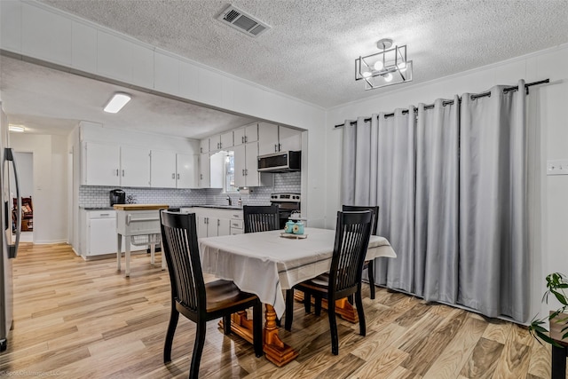 dining area featuring crown molding, a textured ceiling, and light hardwood / wood-style floors