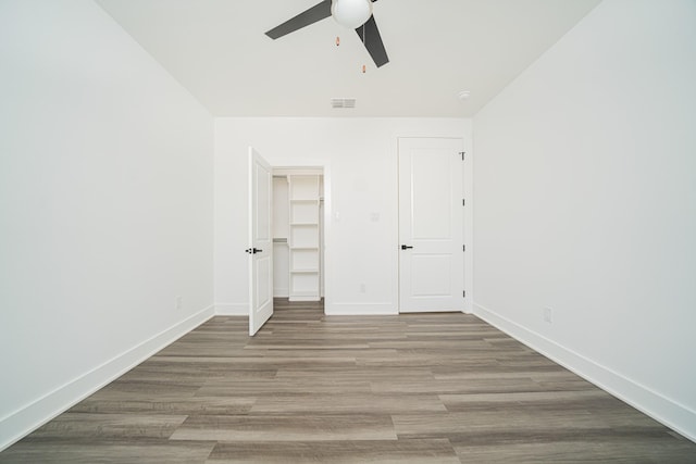 unfurnished bedroom with hardwood / wood-style flooring, a closet, ceiling fan, and a spacious closet