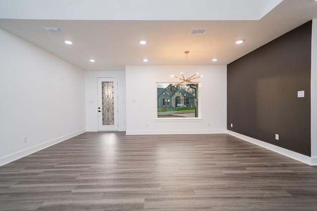 empty room with dark hardwood / wood-style floors and a notable chandelier