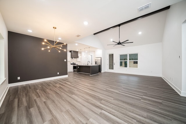 unfurnished living room with beam ceiling, ceiling fan with notable chandelier, dark wood-type flooring, and high vaulted ceiling