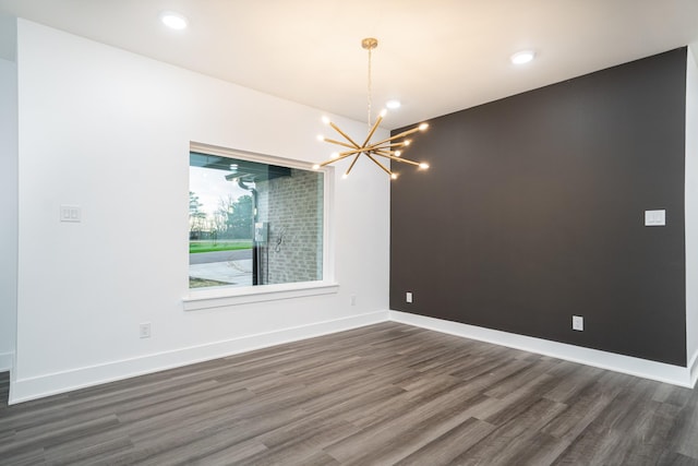 spare room featuring dark hardwood / wood-style flooring and a notable chandelier