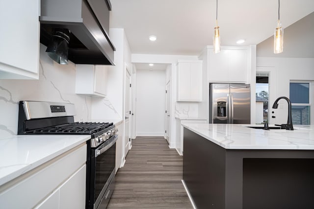 kitchen with sink, appliances with stainless steel finishes, an island with sink, white cabinets, and wall chimney exhaust hood