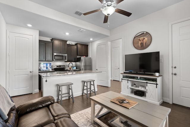 living room featuring ceiling fan, dark hardwood / wood-style floors, and sink