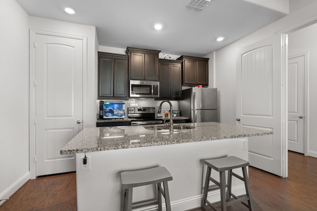 kitchen featuring a kitchen island with sink, a breakfast bar area, and appliances with stainless steel finishes