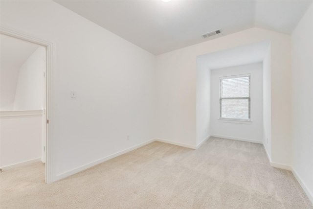 spare room featuring lofted ceiling and light carpet