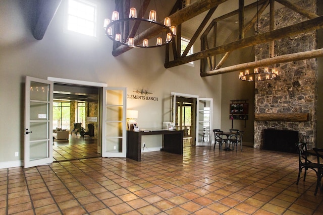 unfurnished living room with a fireplace, lofted ceiling with beams, a chandelier, tile patterned floors, and french doors