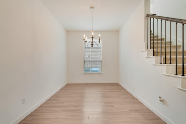 unfurnished dining area with a notable chandelier and light hardwood / wood-style floors