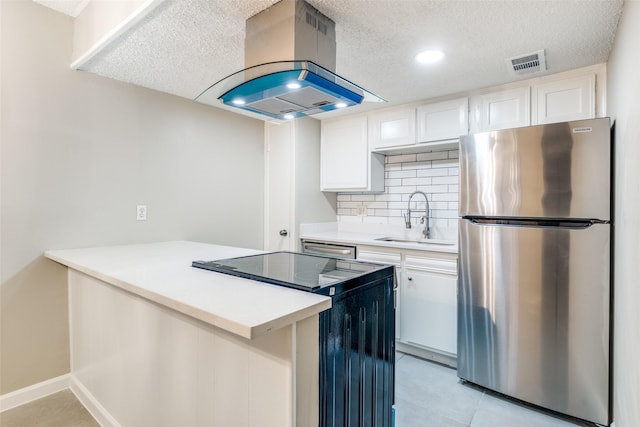 kitchen with sink, range with electric stovetop, stainless steel fridge, island exhaust hood, and white cabinets