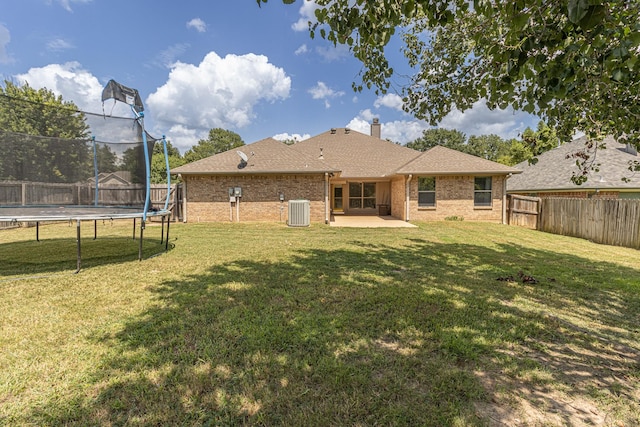 19482 Ruggles Ct, Flint, TX 75762 - rear view of house with a trampoline, central AC, a patio, brick siding, and a chimney