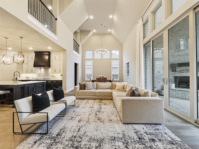 living room featuring sink, light hardwood / wood-style floors, high vaulted ceiling, and a notable chandelier