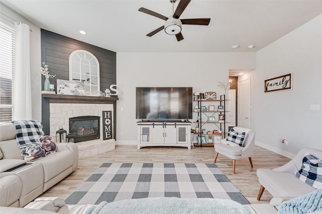 living room with recessed lighting, light wood-style floors, a large fireplace, ceiling fan, and baseboards