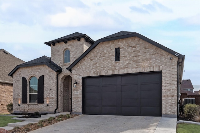 french country style house featuring a garage, concrete driveway, and brick siding