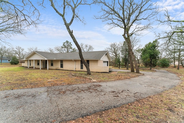 view of front of home featuring brick siding, a front yard, and aphalt driveway