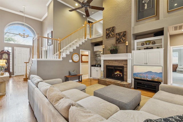 living room with crown molding, light wood-type flooring, visible vents, and a healthy amount of sunlight