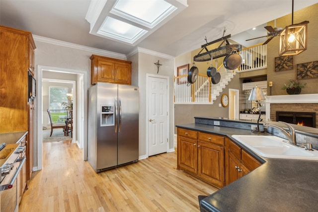 kitchen featuring brown cabinets, dark countertops, light wood-style floors, a sink, and stainless steel fridge