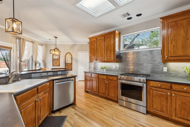 kitchen with brown cabinetry, dark countertops, ornamental molding, stainless steel appliances, and a sink