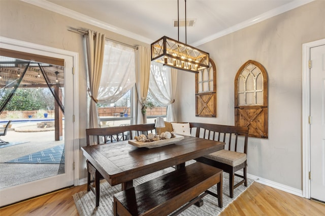 dining room with visible vents, baseboards, wood finished floors, an inviting chandelier, and crown molding