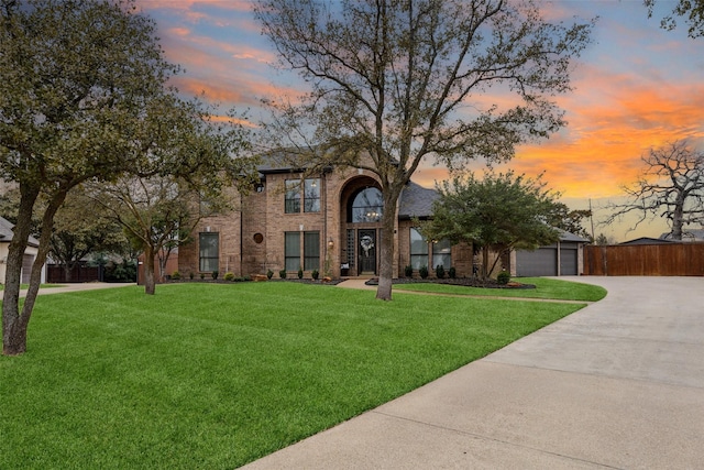 view of front of property with a garage, brick siding, fence, and a front lawn