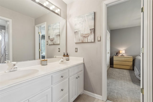 ensuite bathroom with double vanity, baseboards, a sink, and ensuite bathroom