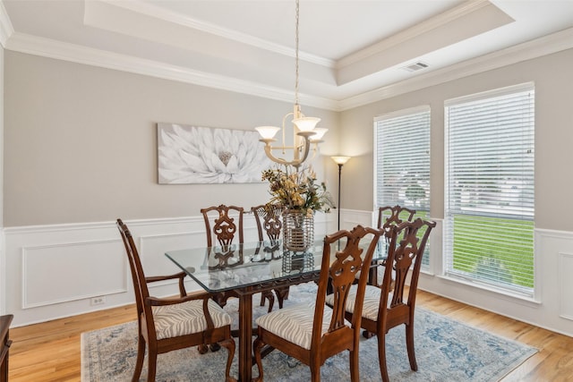 dining space with light wood finished floors, visible vents, wainscoting, an inviting chandelier, and a tray ceiling