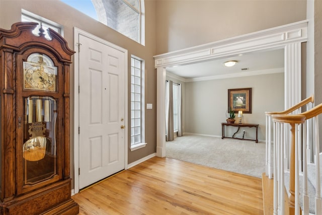 foyer entrance featuring baseboards, visible vents, stairway, ornamental molding, and wood finished floors