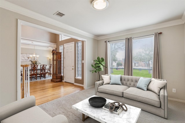 living room with ornamental molding, visible vents, light wood finished floors, and baseboards