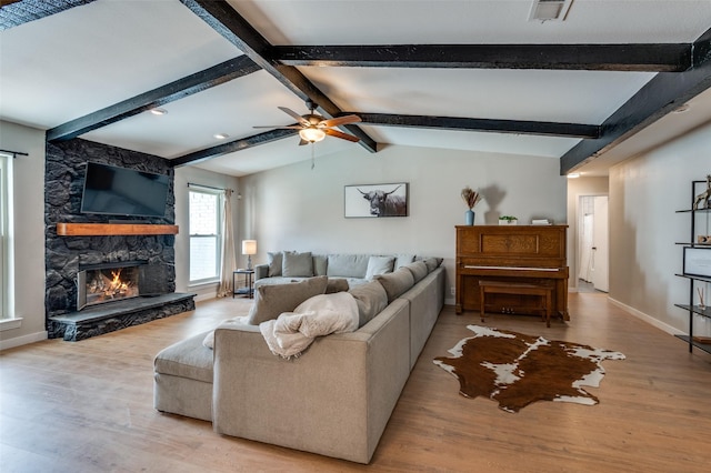 living room featuring vaulted ceiling with beams, ceiling fan, a fireplace, and light wood-type flooring