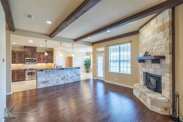 living room featuring hardwood / wood-style flooring, a fireplace, sink, and beamed ceiling