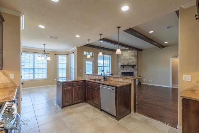 kitchen featuring a fireplace, dishwasher, sink, range, and light tile patterned floors