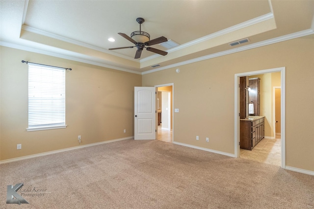 unfurnished bedroom with crown molding, a tray ceiling, and light carpet