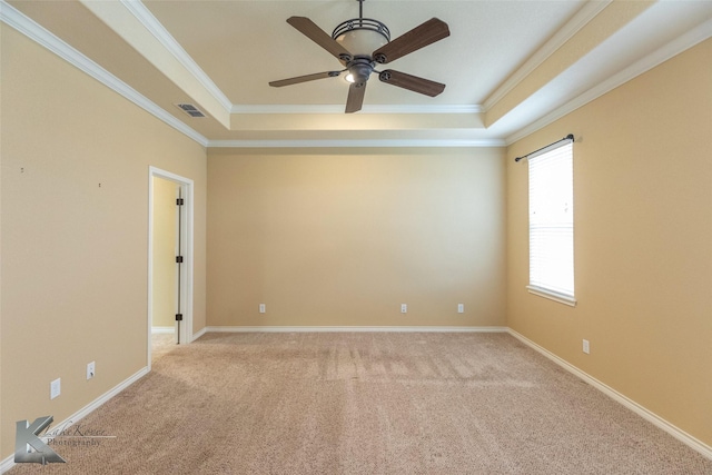 carpeted spare room with a tray ceiling, ornamental molding, and ceiling fan