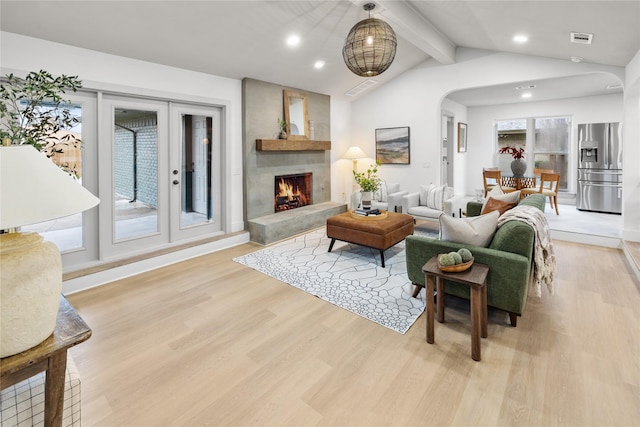 living room with light hardwood / wood-style flooring, lofted ceiling with beams, and a large fireplace