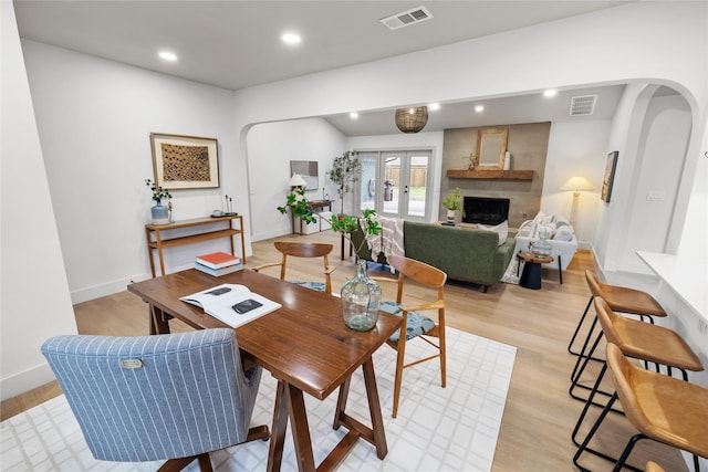 dining area featuring a fireplace, light hardwood / wood-style flooring, and french doors